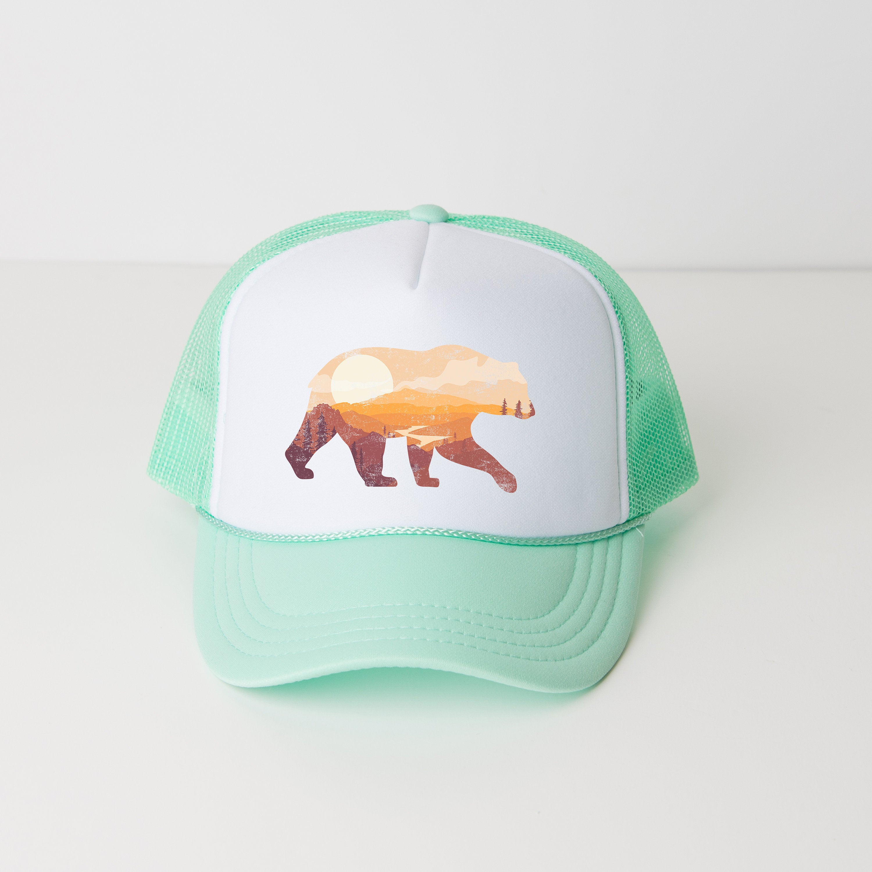 a green and white hat with a picture of a bear on it