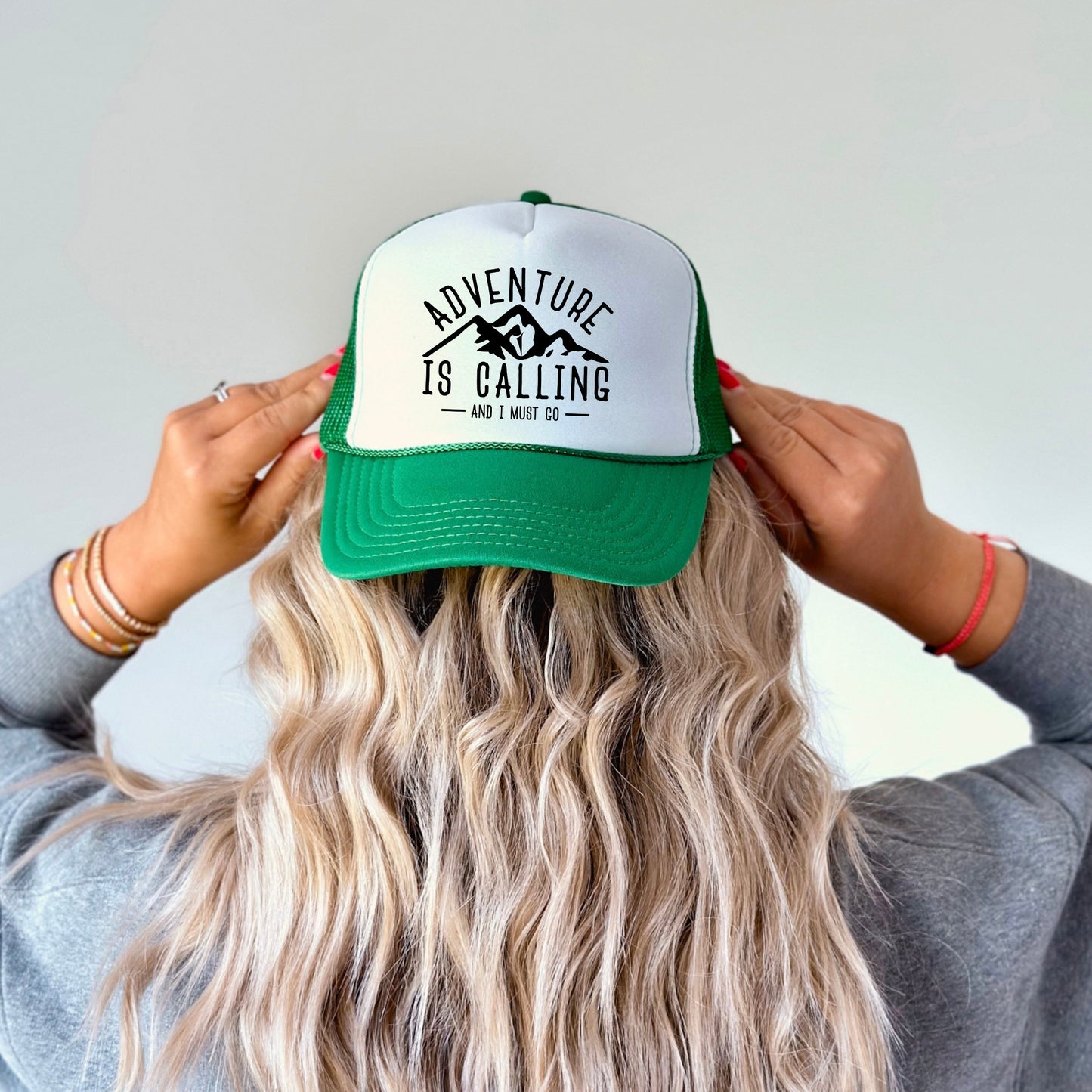 the back of a woman's head wearing a green and white trucker hat