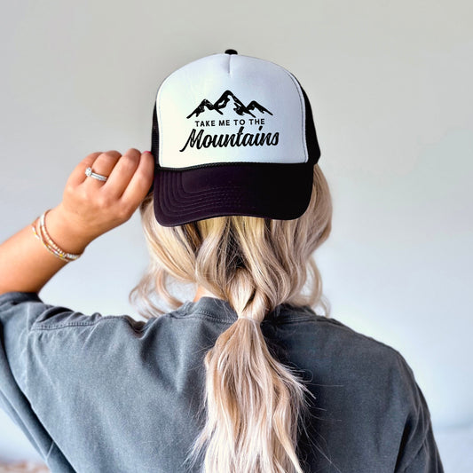 a woman wearing a black and white hat with mountains on it