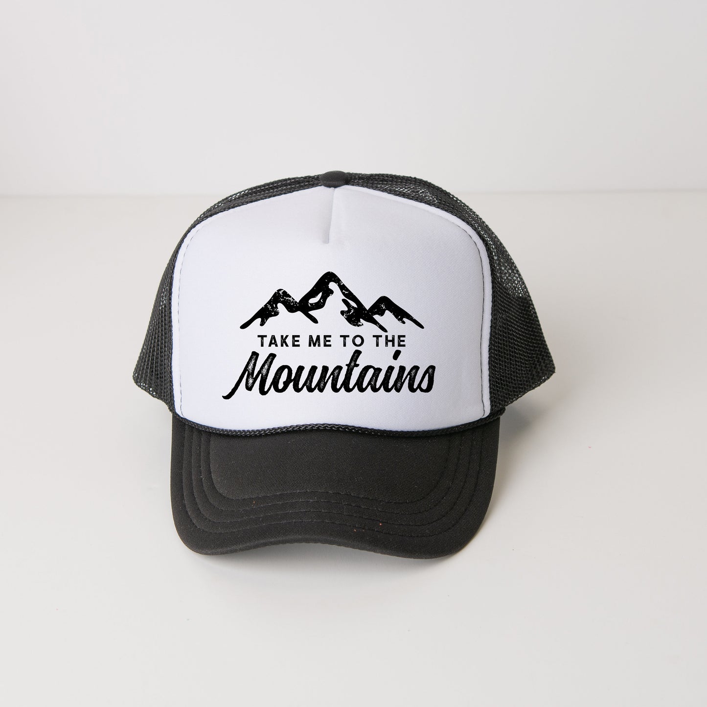 a black and white trucker hat that says take me to the mountains