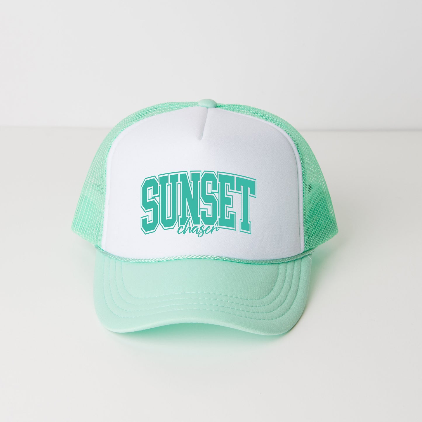 a green and white hat with the word sunset on it