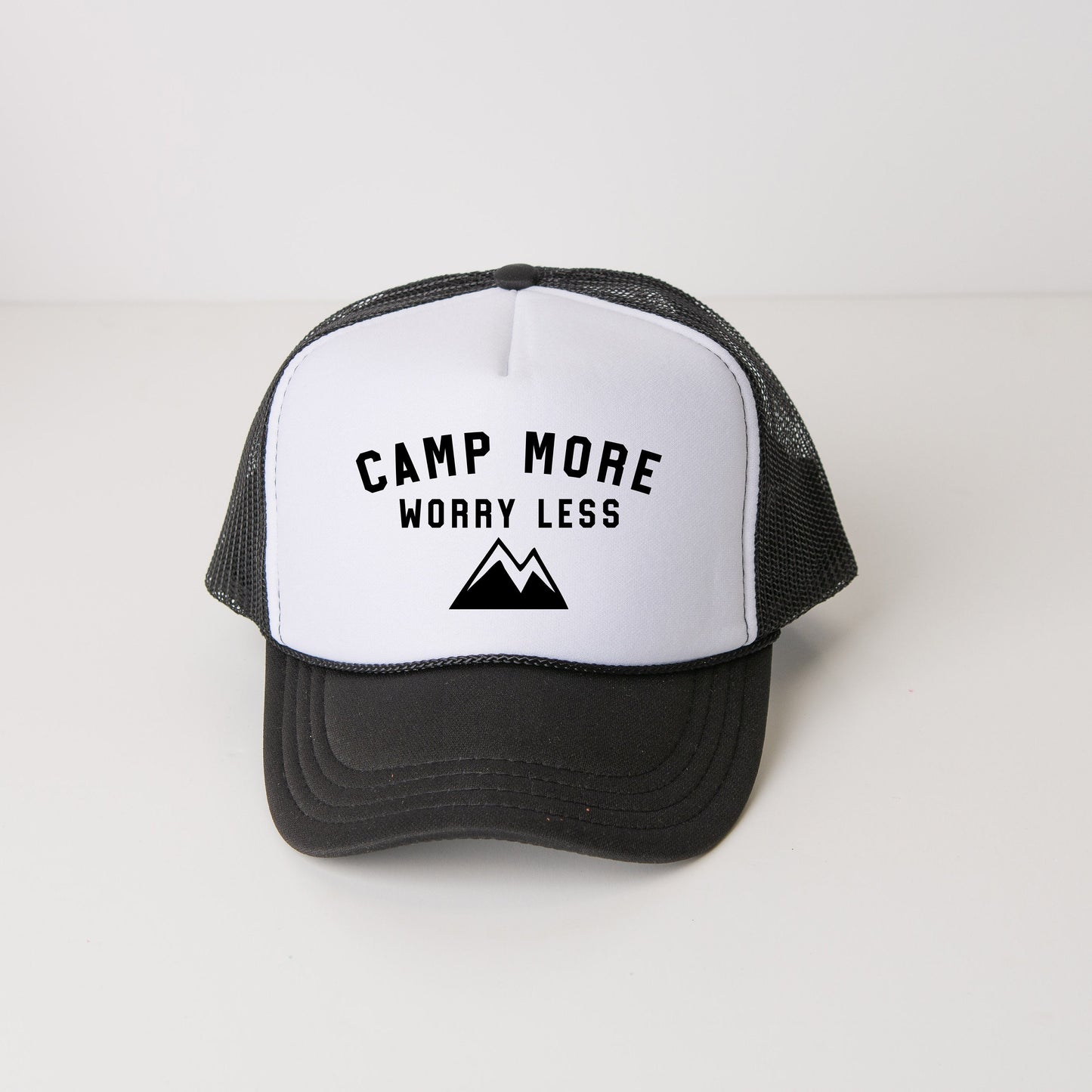 a black and white trucker hat that says camp more worry less