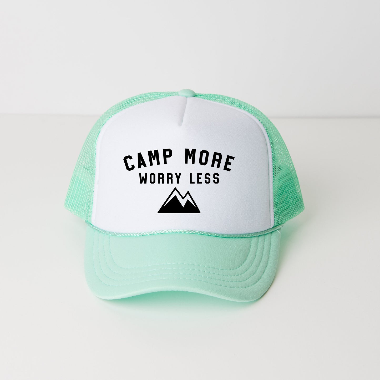 a green and white trucker hat that says camp more worry less