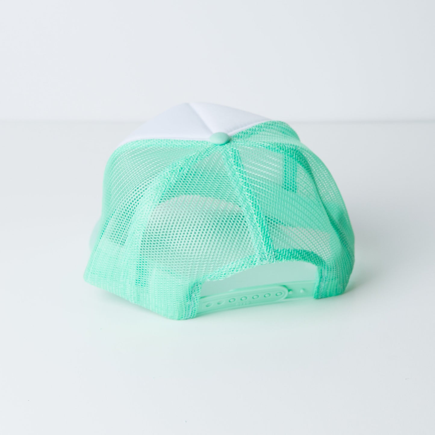 a green and white trucker hat on a white surface